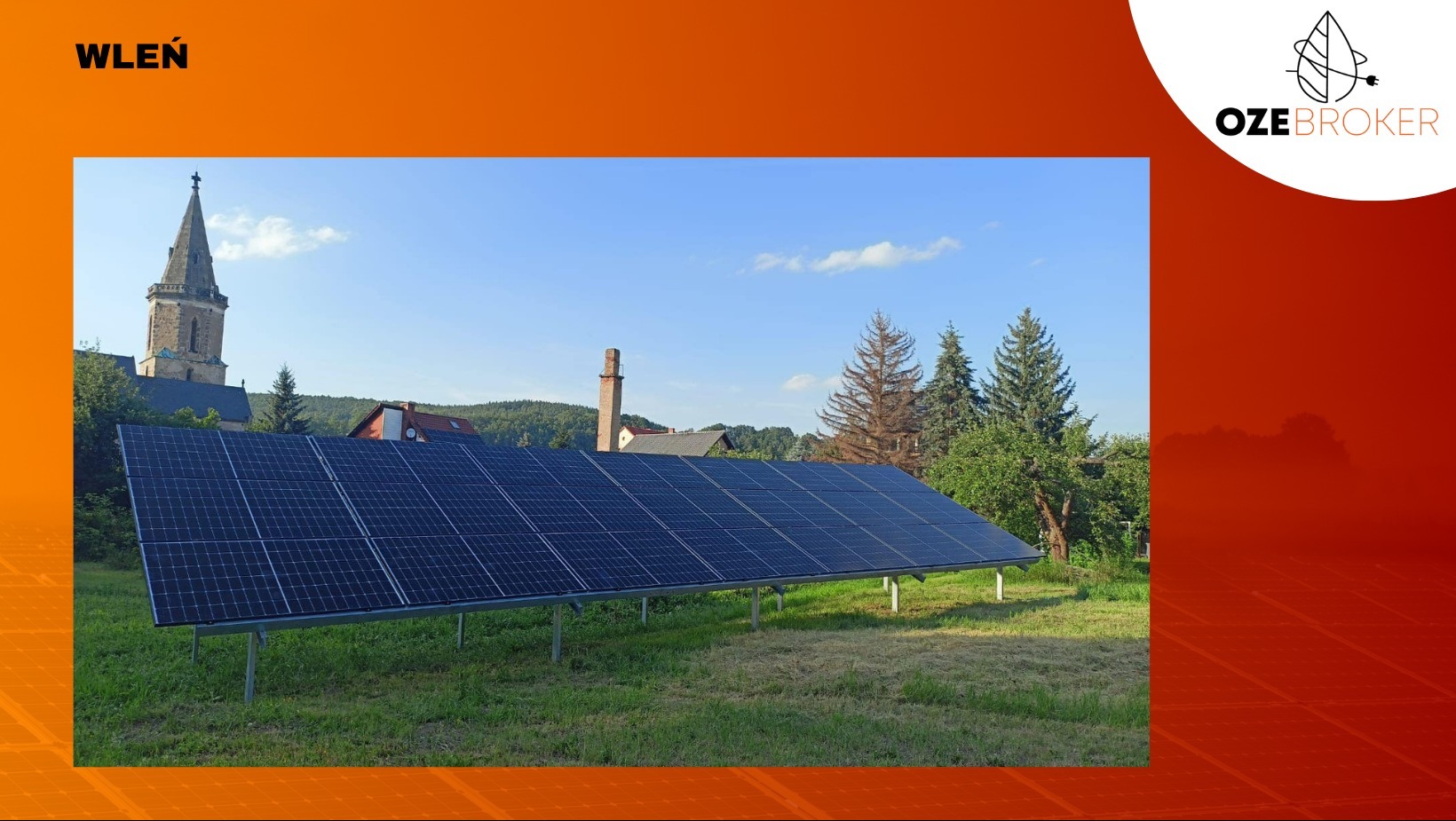 Instalacja paneli słonecznych na trawiastym terenie z kościołem w tle, Wleń.