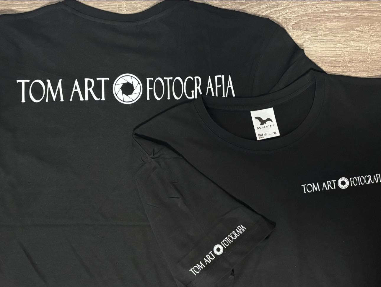 Dwa czarne T-shirty z białym nadrukiem 'TOM ART FOTOGRAFIA', logo firmy odzieżowej Malfini widoczne na jednym z nich.