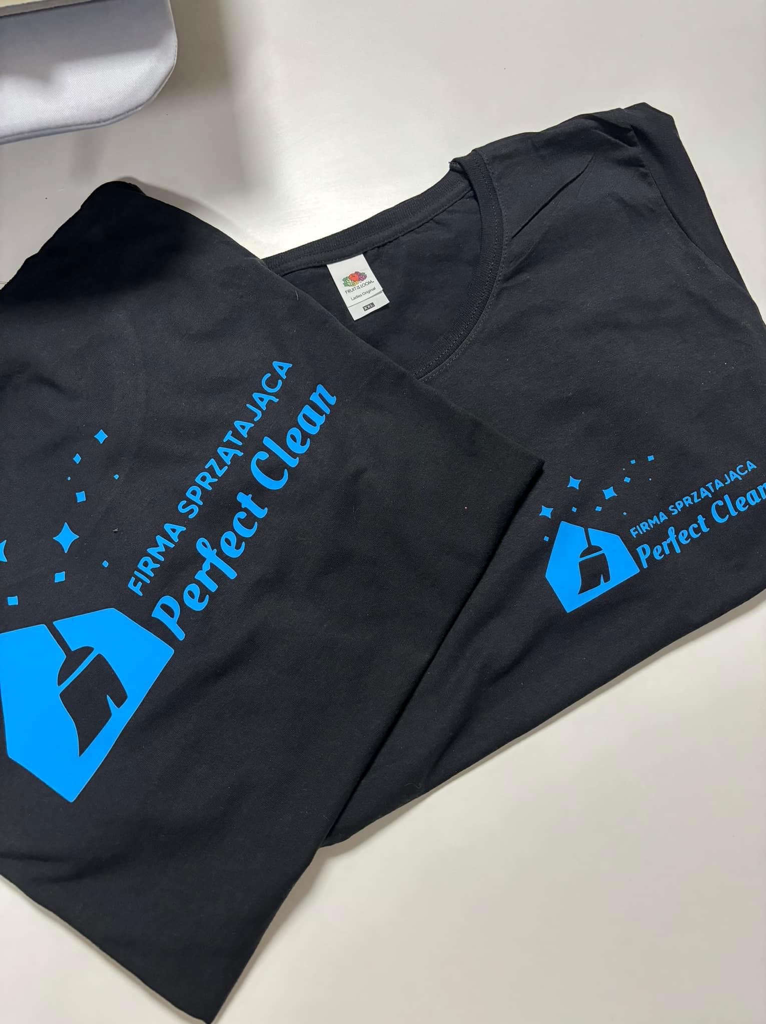 Dwa czarne T-shirty z niebieskim nadrukiem logo firmy sprzątającej Perfect Clean, leżące na białym tle.
