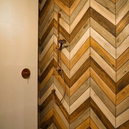 Wykończenia wnętrz od A do Z Tomasz Rzepka - Nowoczesna kabina prysznicowa z drewnopodobnymi płytkami ułożonymi w jodełkę i miedzianą armaturą.