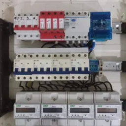 Rozdzielnica elektryczna z zamontowanymi zabezpieczeniami przeciwprzepięciowymi (czerwone), wyłącznikami nadprądowymi (białe i niebieskie) oraz czterema licznikami energii elektrycznej F&F WZE-3...