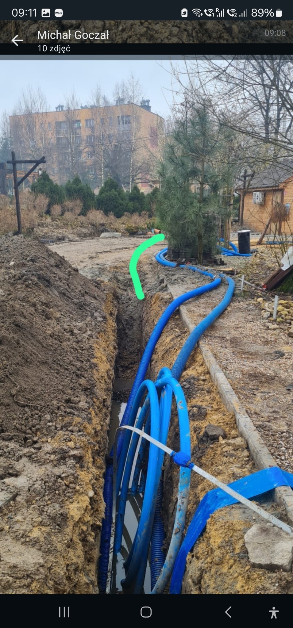 Wykop z niebieskimi rurami kablowymi układanymi w ziemi w Jawiszowicach, widoczne zabezpieczenia i elementy instalacji w gruncie.