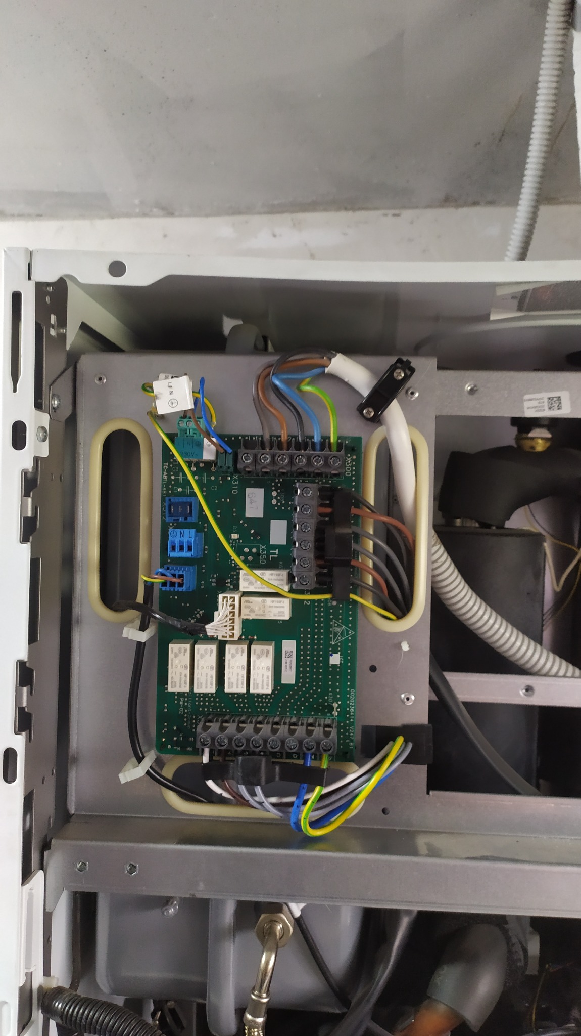 Otwarta obudowa urządzenia z widoczną płytą sterującą, licznymi przewodami w różnych kolorach podłączonymi do złączek, oraz elementami elektronicznymi na płycie