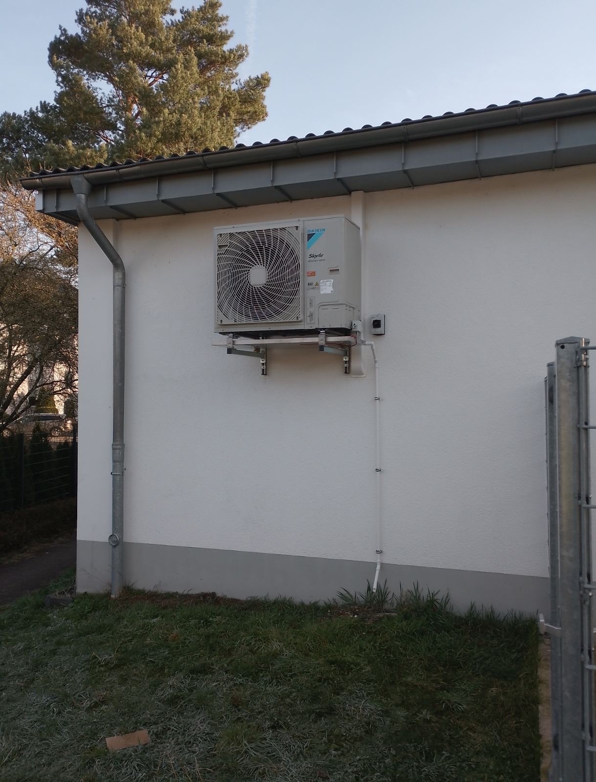 Zewnętrzna jednostka klimatyzacji Daikin SkyAir zamontowana na ścianie budynku z widocznymi przewodami i elementami montażowymi.