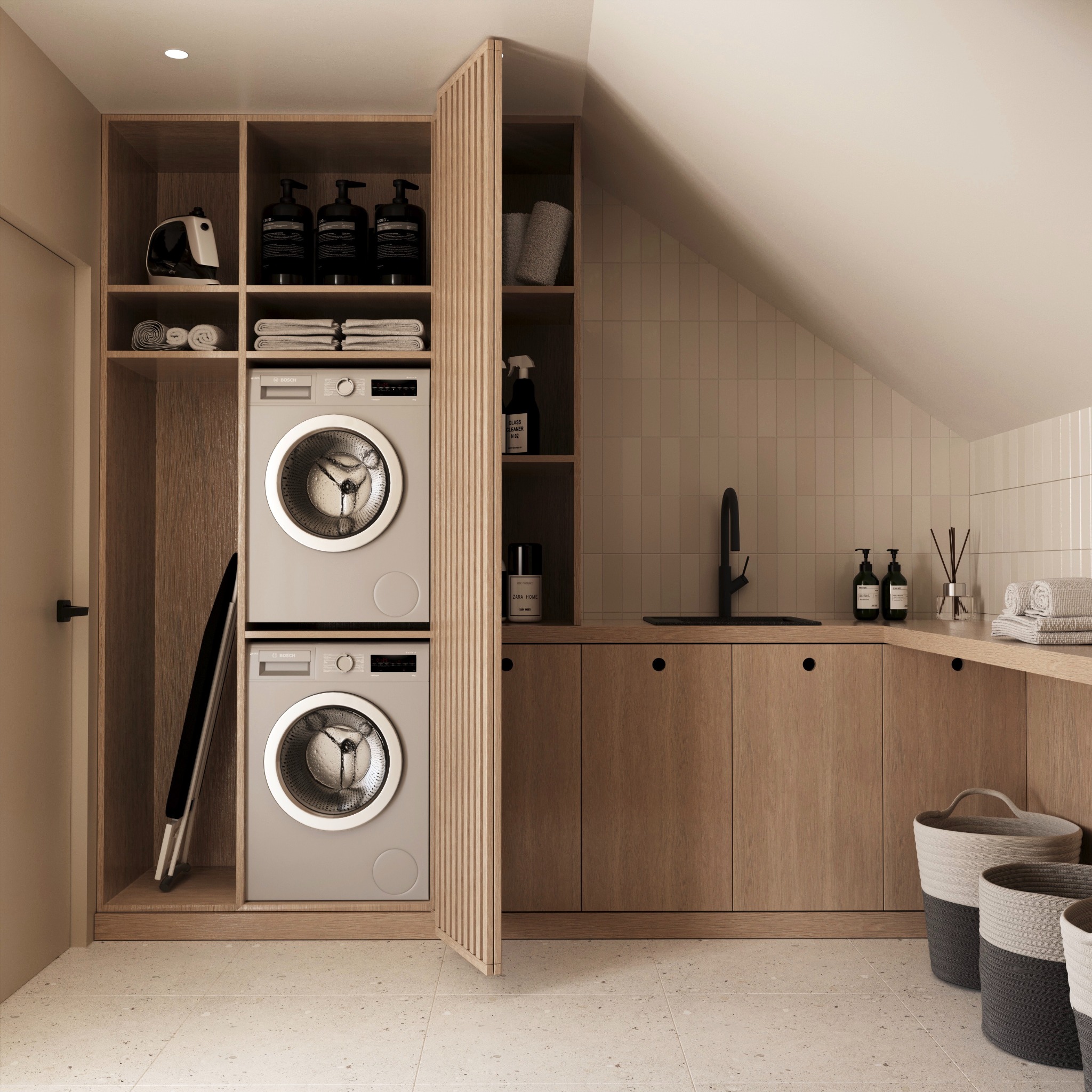 Nowoczesna pralnia w beżowych odcieniach z pralką i suszarką w zabudowie, drewnianymi szafkami, czarną armaturą i dekoracyjnymi koszami na pranie.