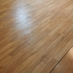 Artur Kowalewski - Ułożona podłoga z płytek imitujących drewno, widoczne niedokończone ściany z instalacją grzewczą i elektryczną w tle.