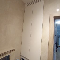 Yauheni Smirnou - Biała szafa wnękowa z wentylacją u góry, zabudowana nad pralką w łazience z beżowymi płytkami.