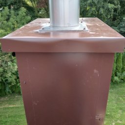 Sebbud - Brązowa obróbka blacharska komina z metalowym wkładem, widoczne ślady zabrudzeń na górnej powierzchni.