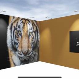 Mel-Expo Emilia Statucka-Sklepik - Stoisko targowe z dużym formatem portretu tygrysa na czarnym tle, oświetlone reflektorami, obok ściana z logo MEL-EXPO.