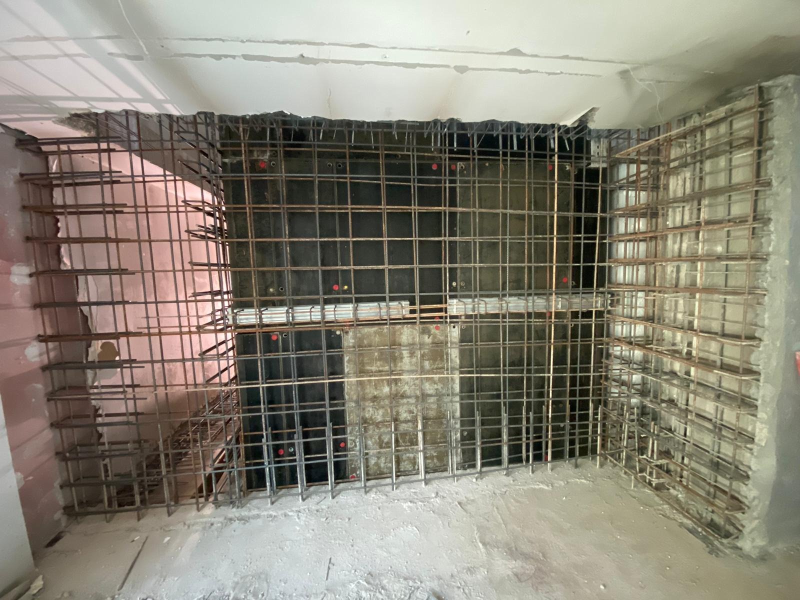 Zbrojenie nowej klatki schodowej w budynku, widoczne siatki zbrojeniowe z prętów stalowych oraz szalunki z płyt, przygotowane do zalania betonem.