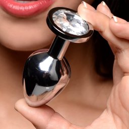 Room36 Sp. z o.o. - Błyszczący, metalowy obiekt z dużym, fasetowanym kryształem trzymany przez osobę z pomalowanymi ustami i zadbanymi paznokciami.