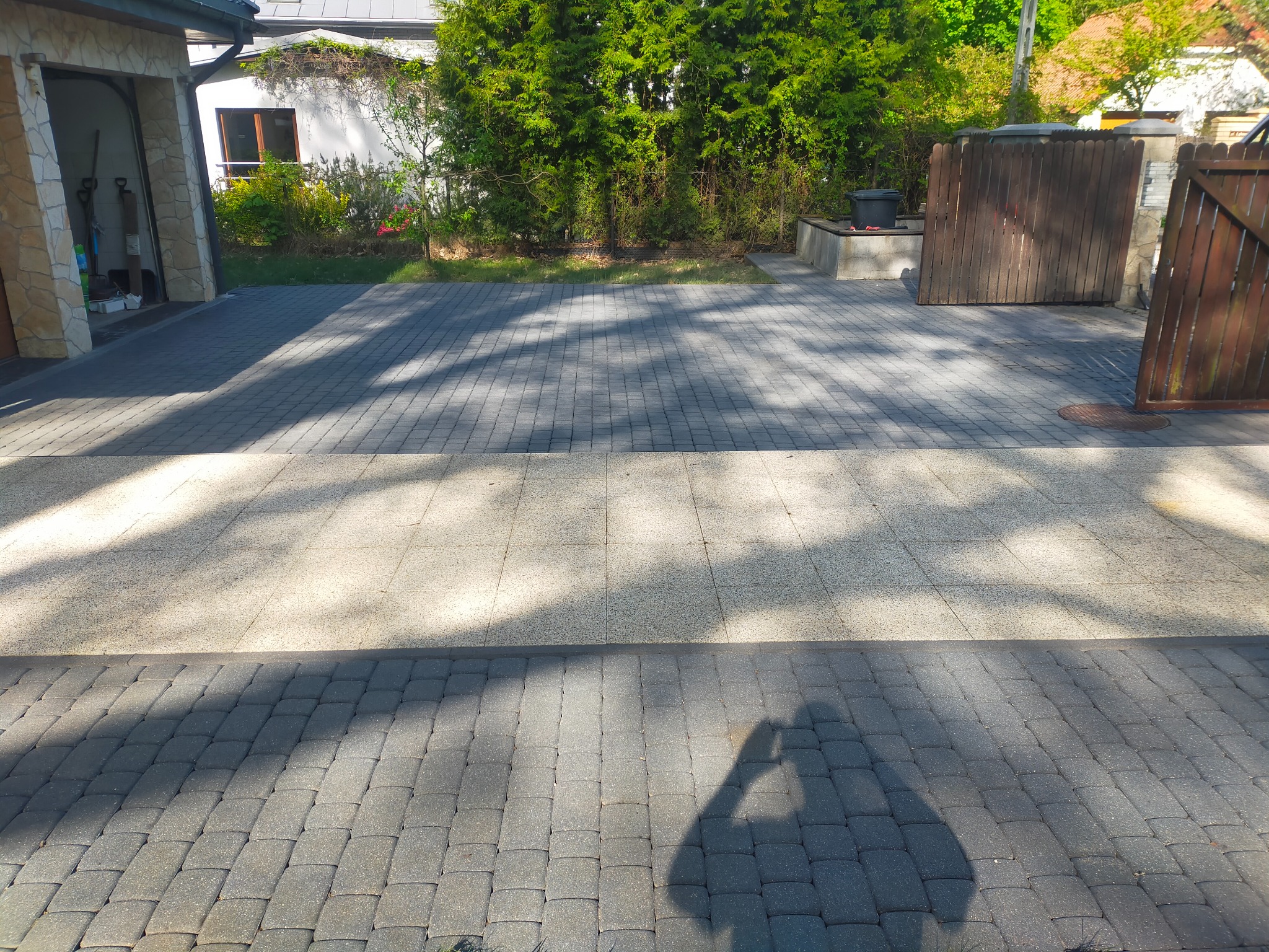 Dwukolorowa kostka brukowa na podjeździe w Warszawie, z cieniem osoby robiącej zdjęcie.