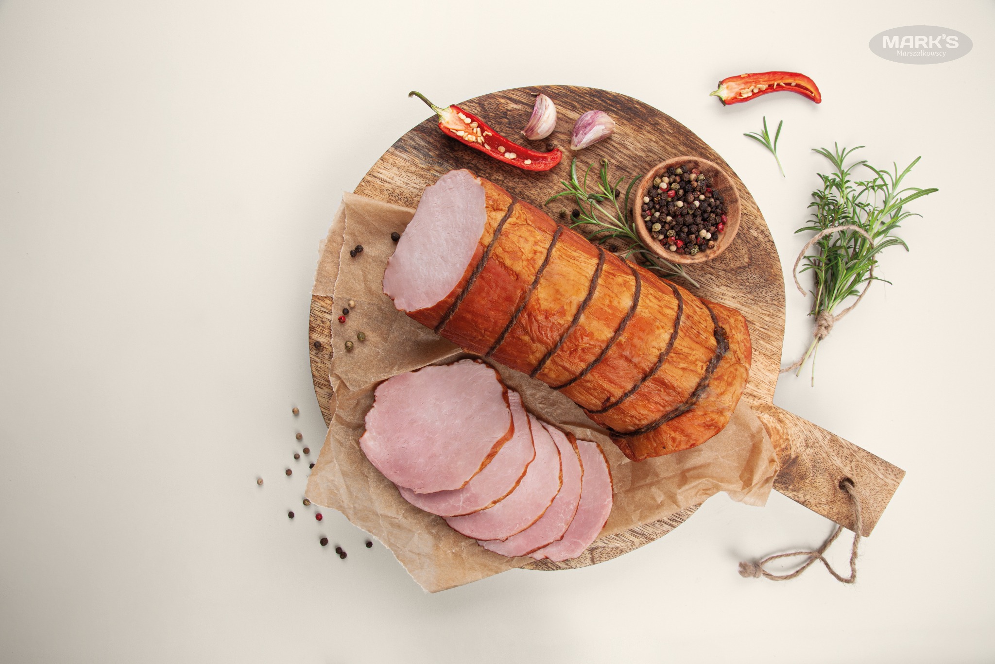Wędzony blok mięsa pokrojony w plastry, ułożony na drewnianej desce z przyprawami i ziołami, widok z góry, minimalistyczna kompozycja.