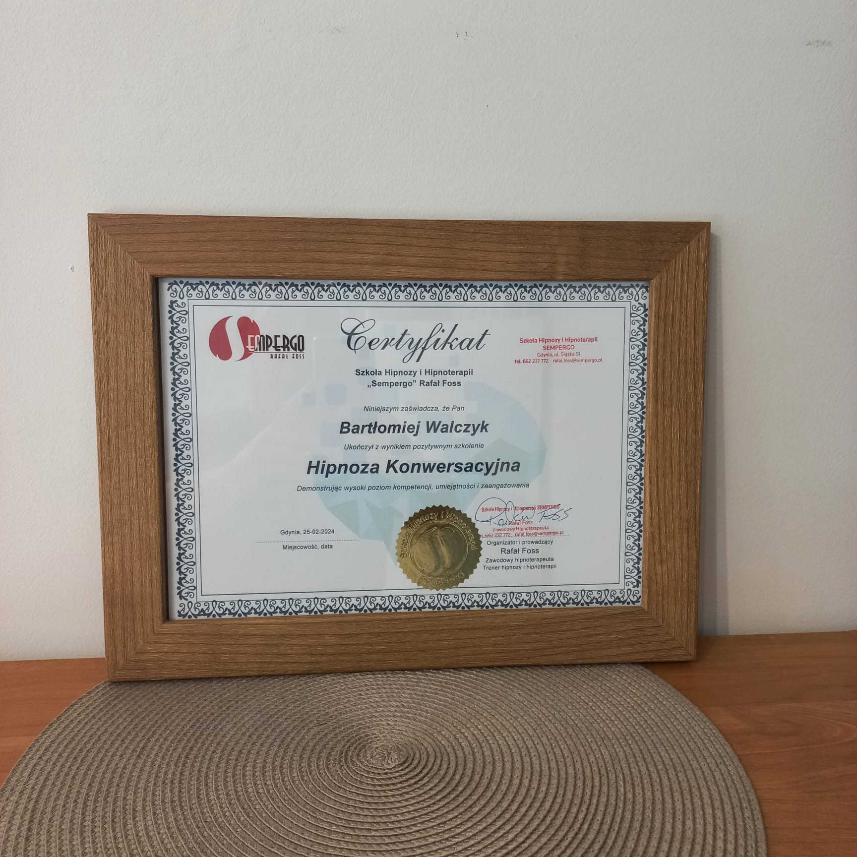 Oprawiony w drewnianą ramkę certyfikat ukończenia szkolenia z hipnozy konwersacyjnej dla Bartłomieja Walczyka, wydany przez Szkołę Hipnozy i Hipnoterapii Sempergo Rafał Foss, z siedzibą w Gdyni,...