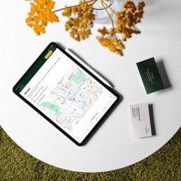 Buzz Makers Digital Marketing Sonia Sokół - Tablet z otwartą stroną kontaktową psychoterapeuty Izabeli Traczyk, mapa Rybnika, wizytówki i żółte kwiaty na białym stole.