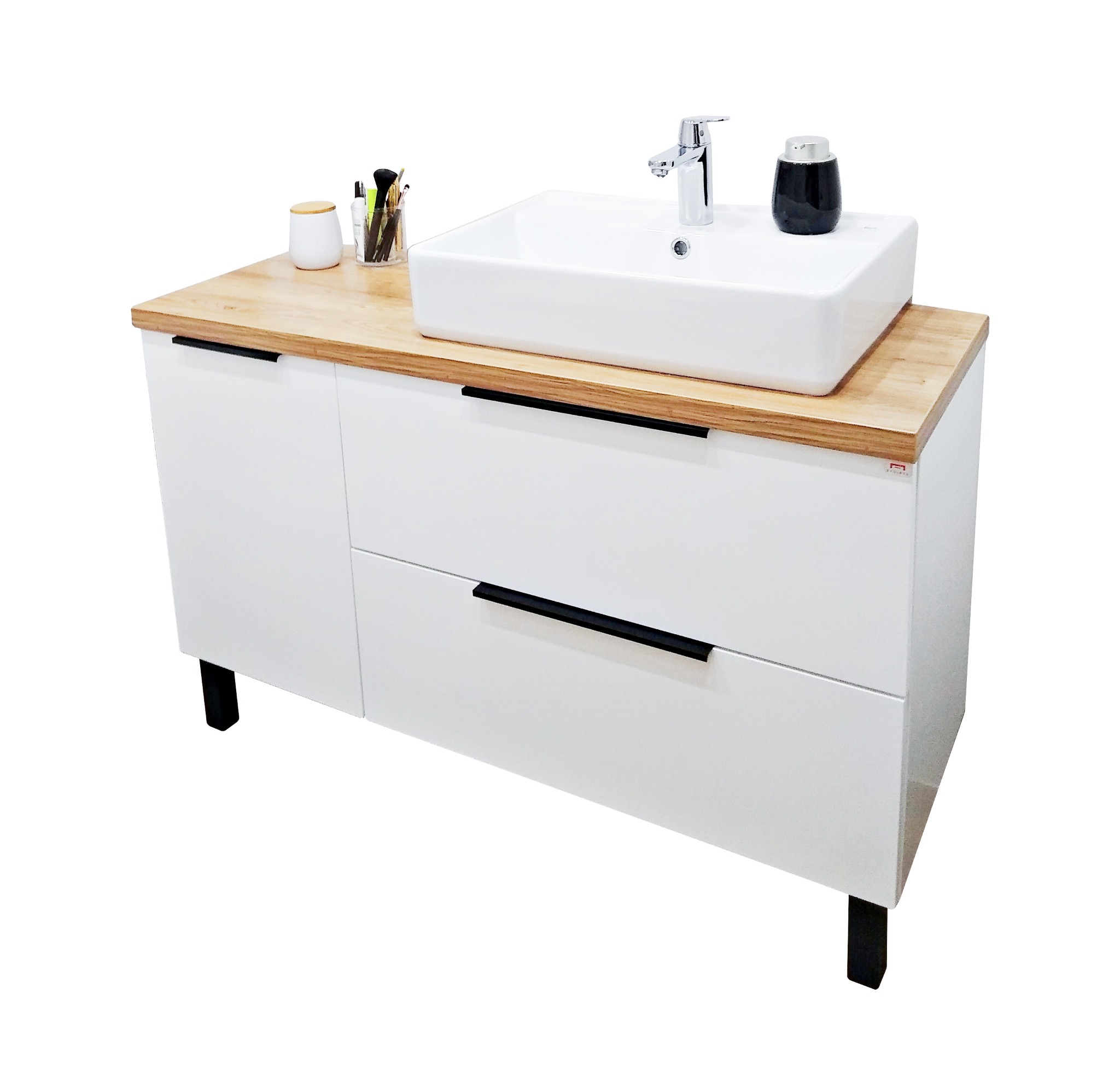 Nowoczesna szafka łazienkowa z białymi frontami, blatem z jasnego drewna i czarnymi uchwytami, na której umieszczono białą, prostokątną umywalkę nablatową, chromowaną baterię i czarny pojemnik...