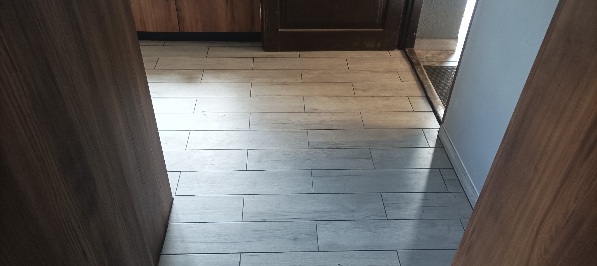 Ułożona podłoga z szarych, podłużnych płytek imitujących drewno w mieszkaniu w Żmigrodzie, widok z progu drzwi.