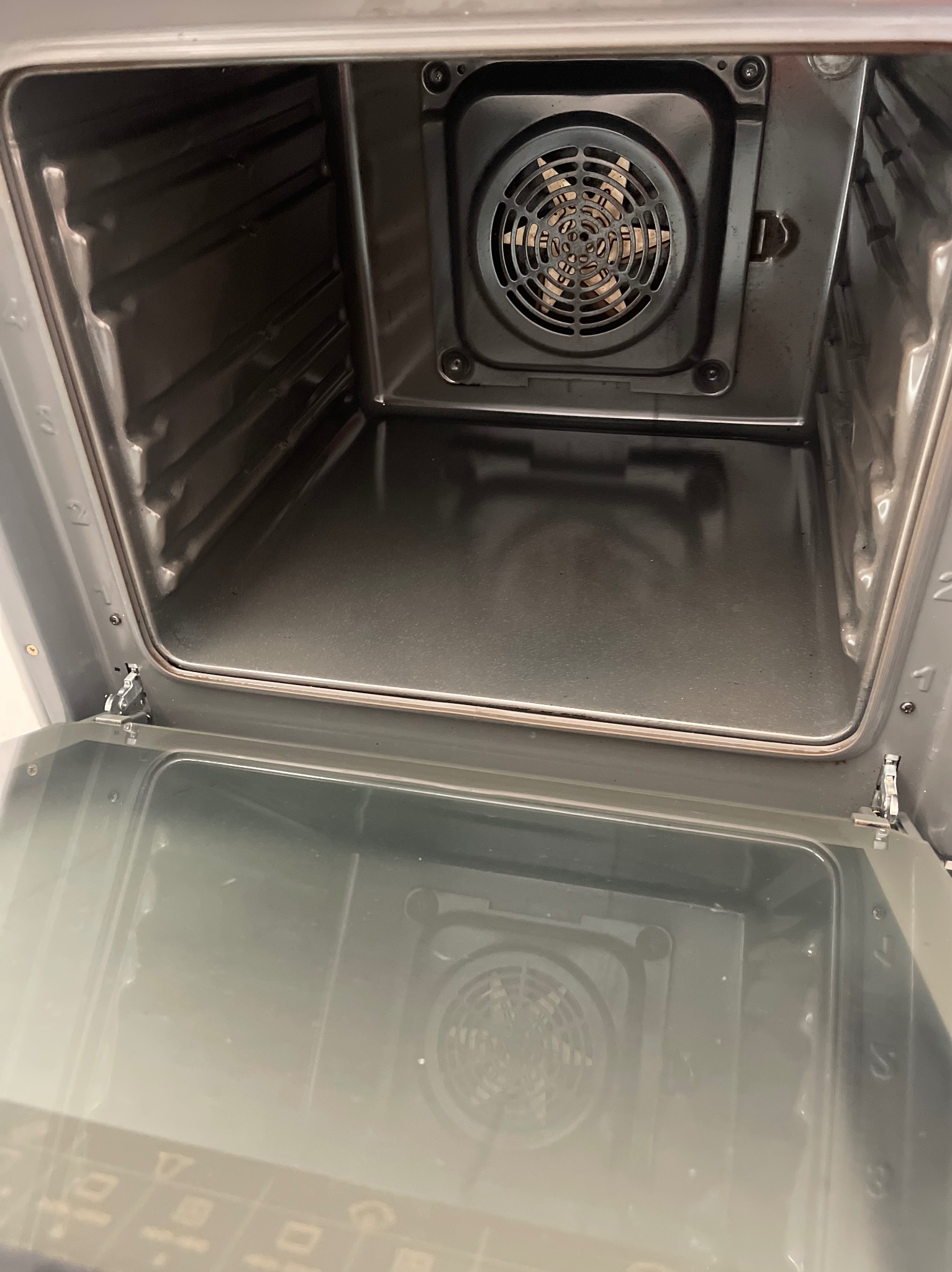 Wnętrze piekarnika z widocznym wentylatorem i grzałką, po procesie czyszczenia. Metalowe elementy są czyste i błyszczące.