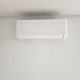 Biała jednostka klimatyzacyjna TCL zamontowana na jasnej ścianie z surowym wykończeniem, widok z dołu.