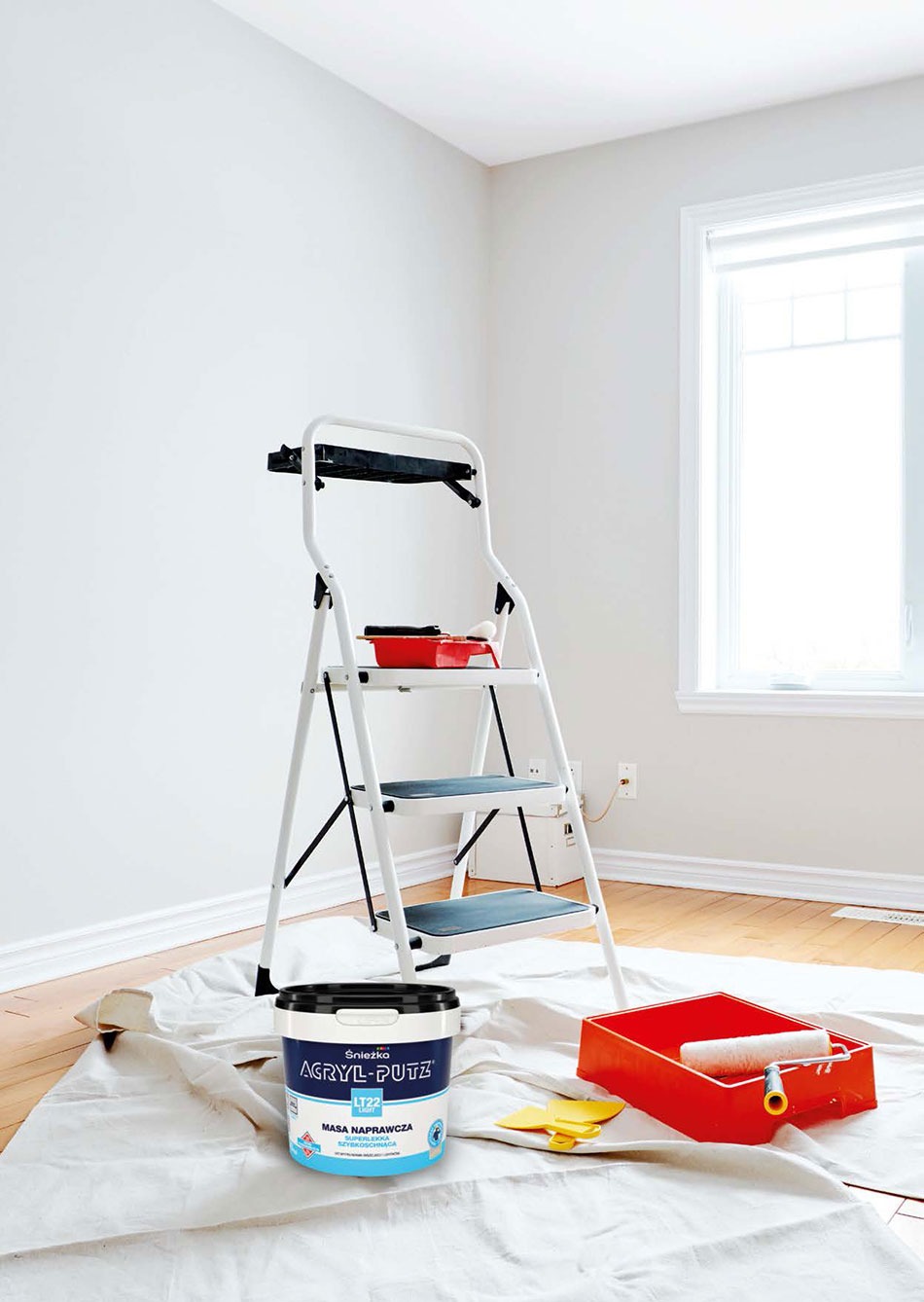 Przygotowania do malowania ścian: drabina, wiadro z masą szpachlową Acryl-Putz, kuweta malarska z wałkiem i żółte szpachelki na podłodze zabezpieczonej płachtą malarską.