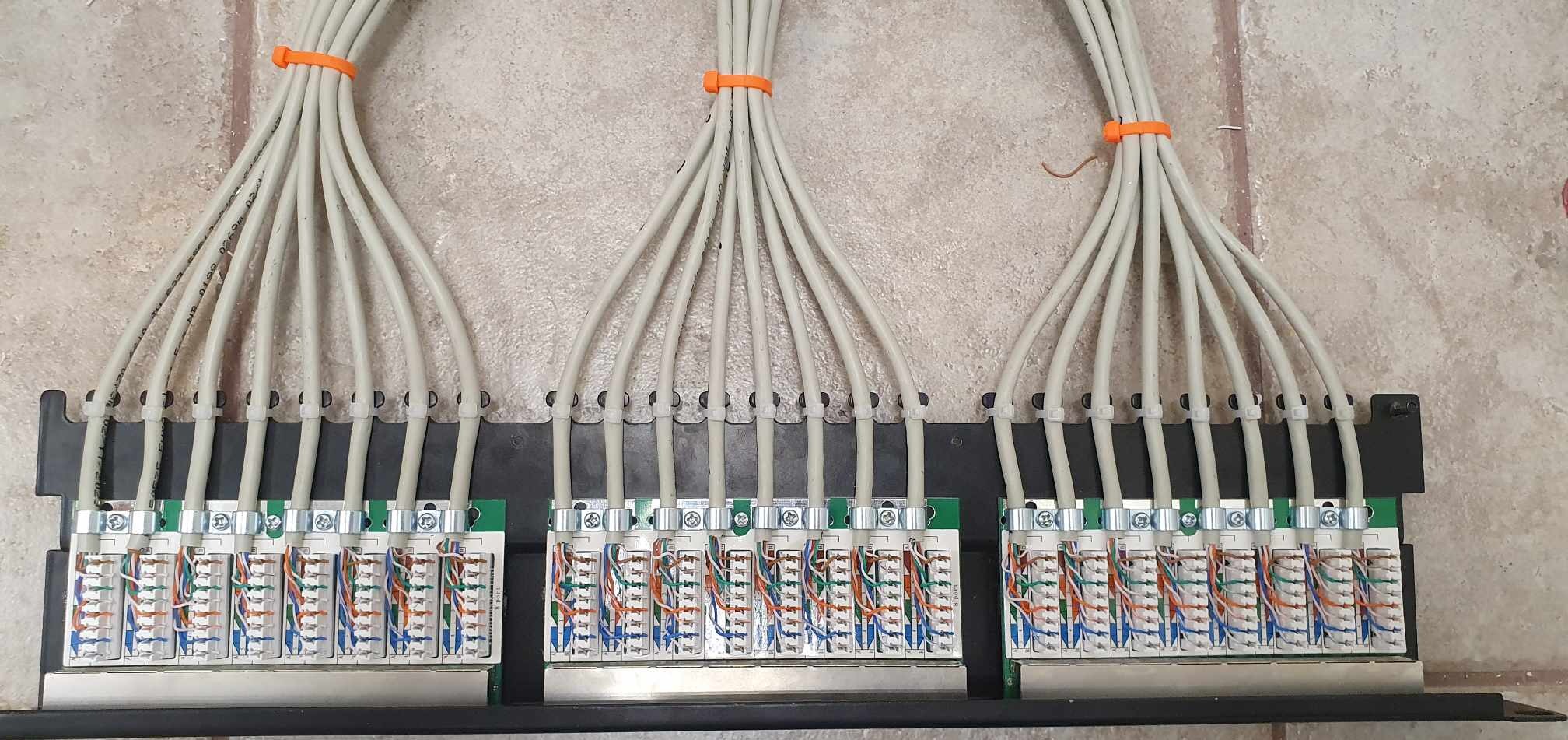 Uporządkowane okablowanie strukturalne w szafie teletechnicznej z patchpanelami i oznaczonymi kablami, przygotowane pod stabilną sieć LAN, widok z bliska.