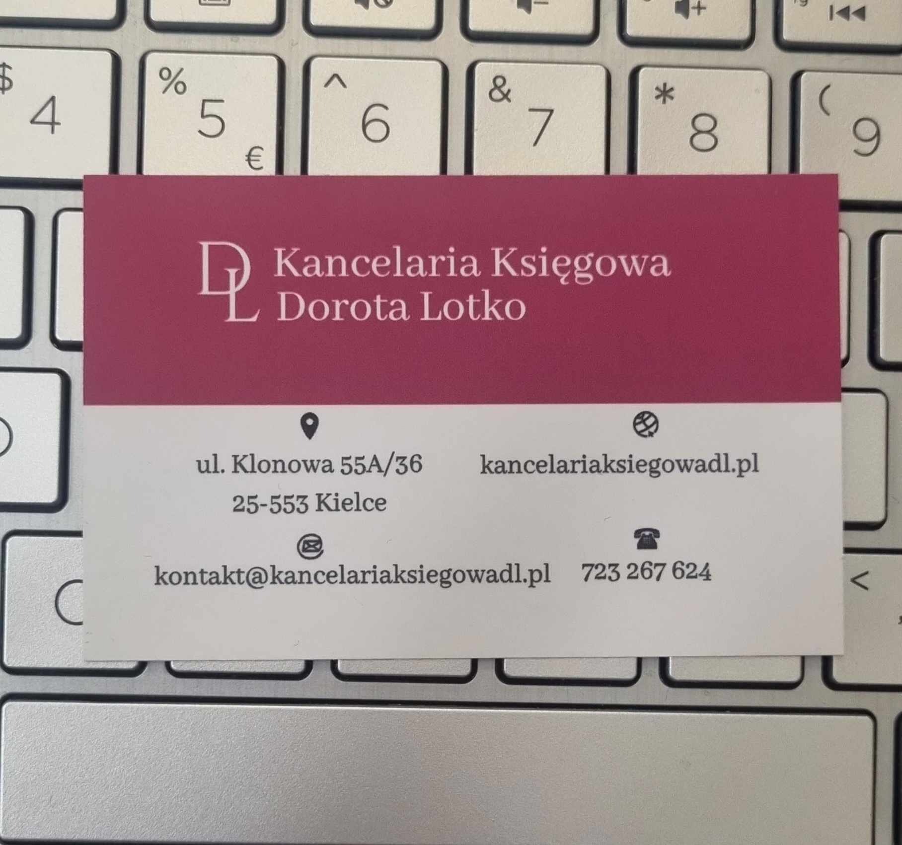 Wizytówka Kancelarii Księgowej Dorota Lotko leżąca na klawiaturze laptopa, prezentująca dane kontaktowe: adres, e-mail, stronę internetową i numer telefonu.