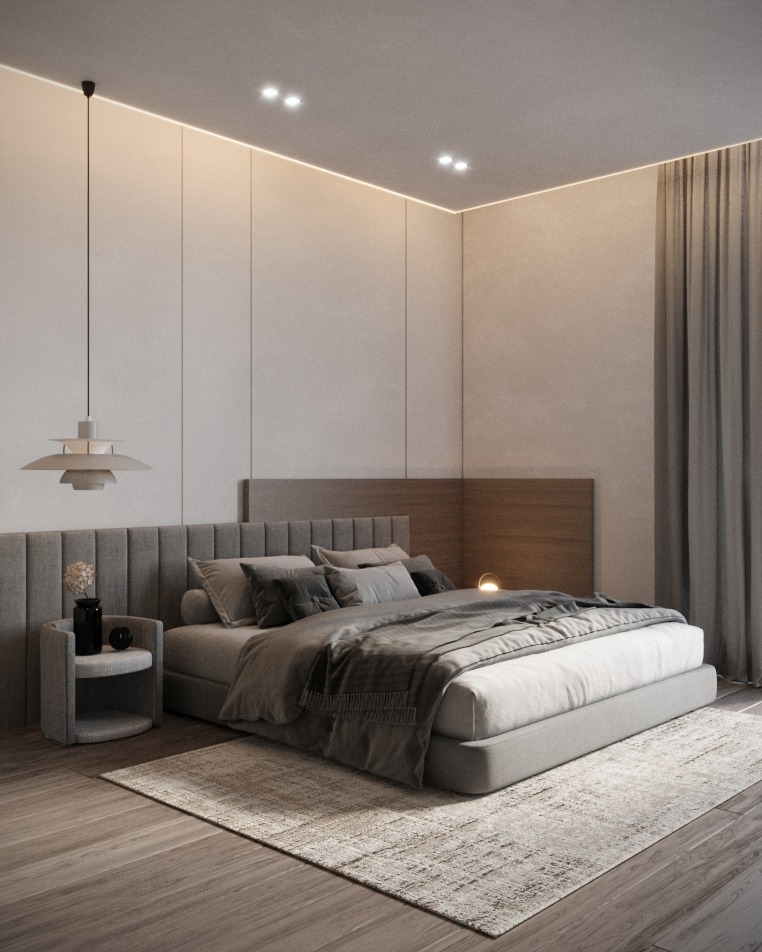 Minimalistyczna sypialnia w stonowanych szarościach: tapicerowane wezgłowie, lampka nocna, dywan z subtelnym wzorem i zwisająca lampa nad szafką nocną.
