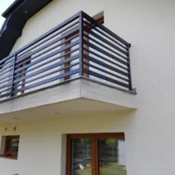 Nowoczesna, czarna balustrada balkonowa z poziomych profili na balkonie domu jednorodzinnego z oknami w brązowych ramach.