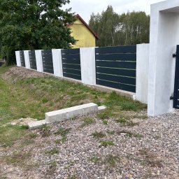 SaldaTech - Nowoczesne ogrodzenie z poziomych, ciemnych paneli między białymi, betonowymi słupkami i bramą, widoczne na tle zieleni i domu.