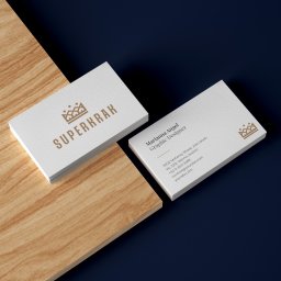 Percepcje Studio Paweł Aleksander Figiel - Stos wizytówek firmy SUPERKRAK dla Marianny Angel, Graphic Designer, na drewnianym blacie i granatowym tle.