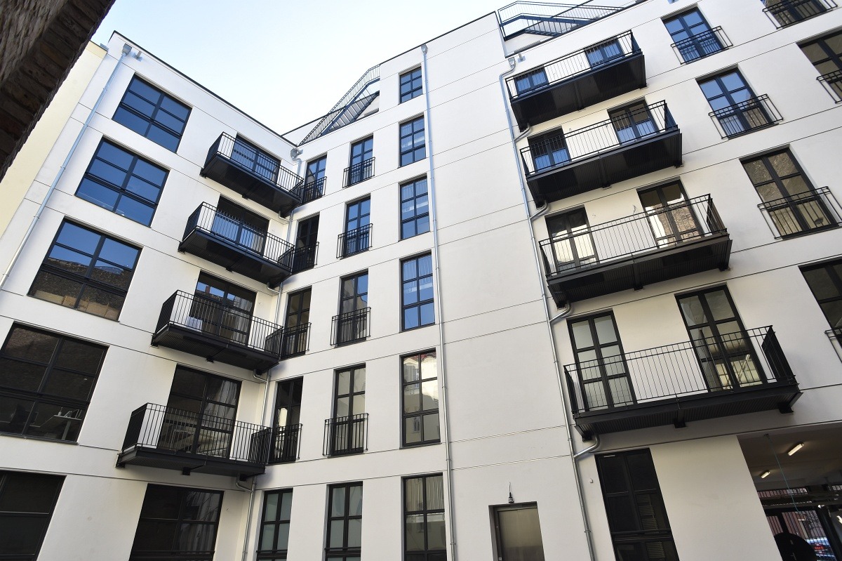 Biały budynek wielorodzinny z czarnymi ramami okien i balkonami, widziany z dołu pod kątem. Minimalistyczna architektura, nowoczesny design.