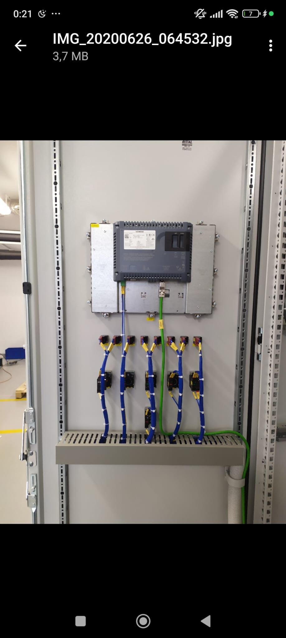 Szara szafa sterownicza z zamontowanym sterownikiem Siemens, okablowaniem w kolorach niebieskim i zielonym, oraz listwą zaciskową.