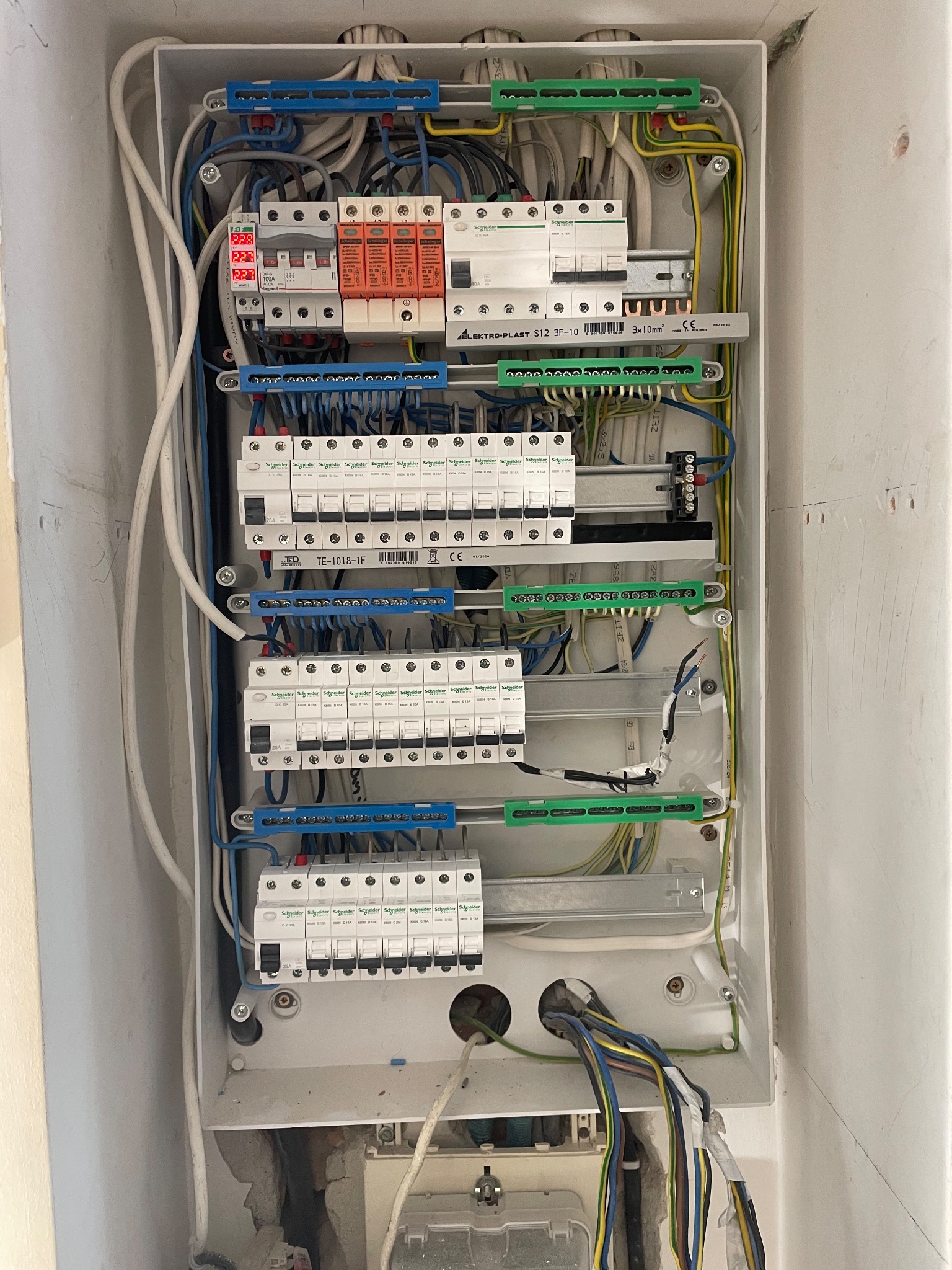 Rozdzielnica elektryczna w obudowie, widoczne zabezpieczenia, przewody i listwy zaciskowe. Ujęcie z góry, ukazujące szczegóły instalacji.