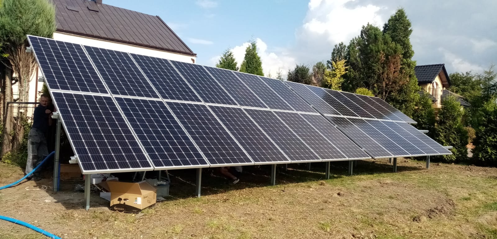 Instalacja paneli słonecznych w Chełmie na gruncie, widoczny pracownik i opakowanie po falowniku Growatt.