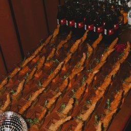 SS GASTRO SPÓŁKA Z OGRANICZONĄ ODPOWIEDZIALNOŚCIĄ - Elegancki catering: rzędy smażonych krewetek w małych naczyniach i butelki napojów na drewnianym stole, obok kula dyskotekowa. Przyciemnione światło.