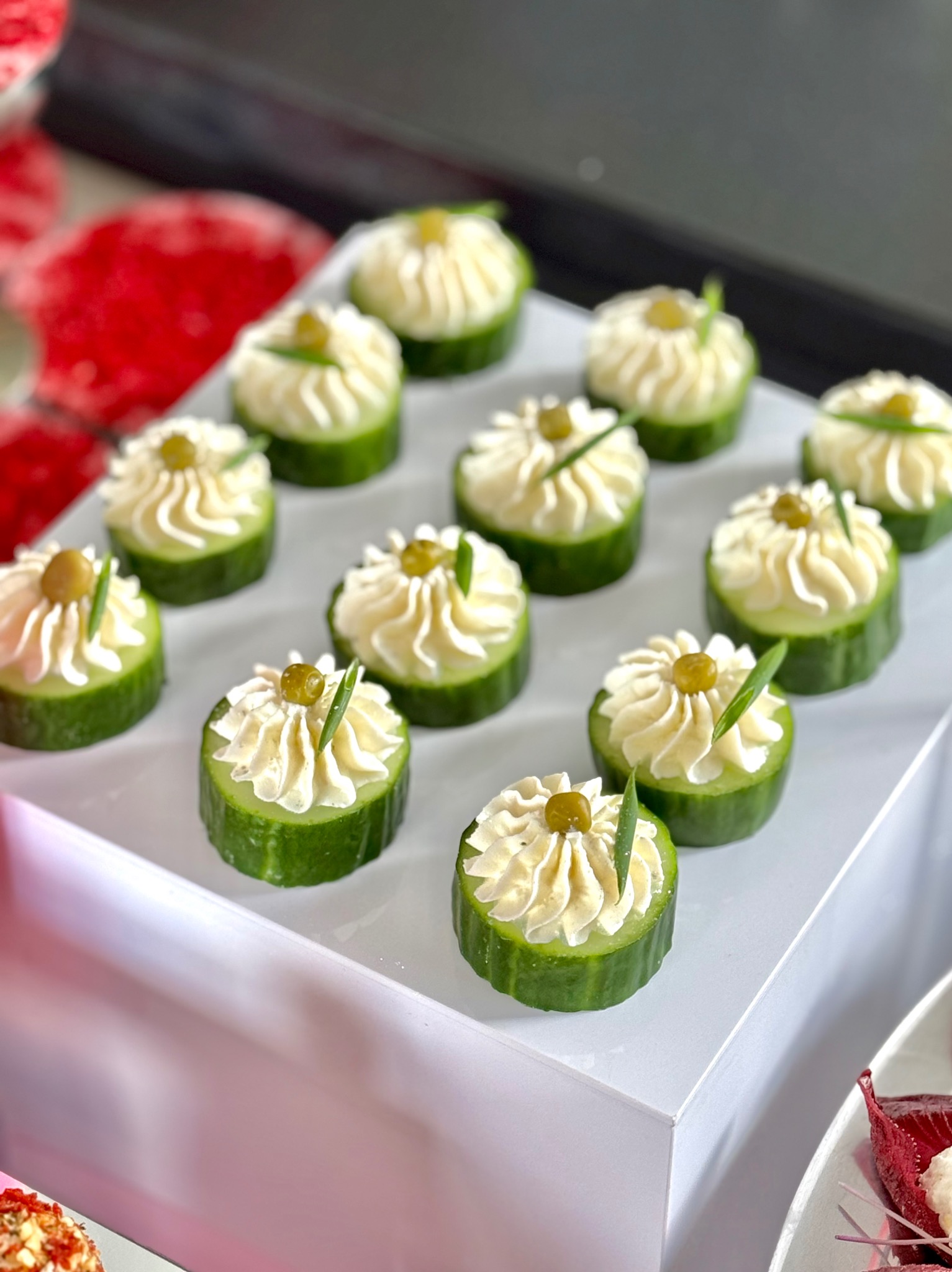 Apetyczne przekąski z ogórka z kremowym nadzieniem i oliwką, prezentowane na białym podeście w Warszawie.