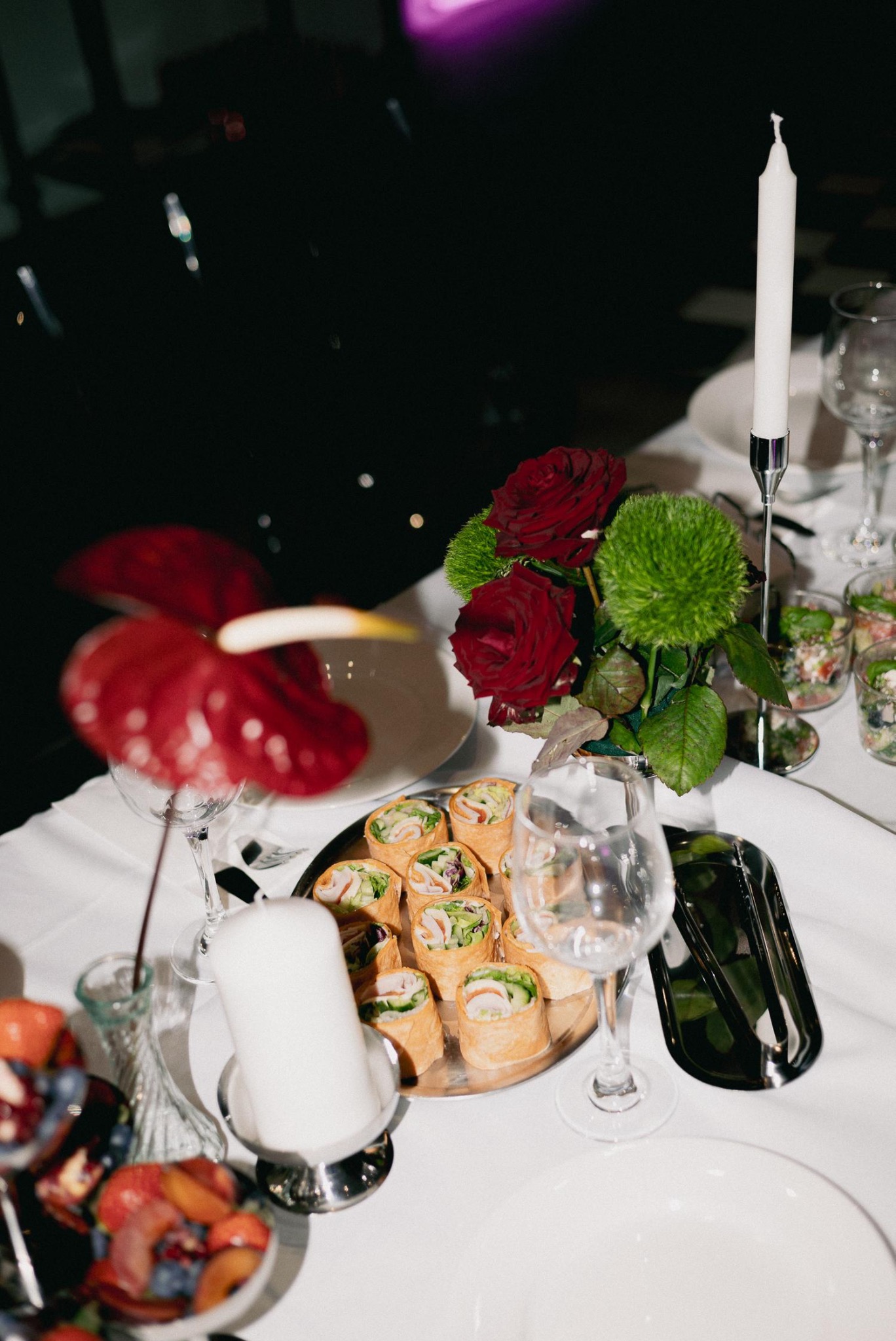 Elegancko nakryty stół z roladkami, kwiatami i świecami. Dekoracja stołu na przyjęcie z bliska, z widocznymi detalami aranżacji i potraw.