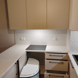 LauMaMebel Volha Lauraniuk - Jasna zabudowa kuchenna z otwartymi szufladami i narożną szafką z półkami obrotowymi, płyta indukcyjna w blacie, minimalistyczne uchwyty.