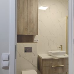 LauMaMebel Volha Lauraniuk - Nowoczesna łazienka z drewnianymi szafkami i umywalką nablatową. Białe marmurowe płytki, złota armatura i oświetlenie LED tworzą elegancki wystrój.