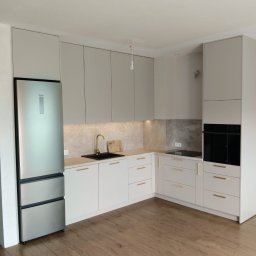 LauMaMebel Volha Lauraniuk - Jasna kuchnia z szarymi szafkami i złotą armaturą. Nowoczesny projekt z lodówką Haier, drewnianą podłogą i subtelnym oświetleniem podszafkowym.