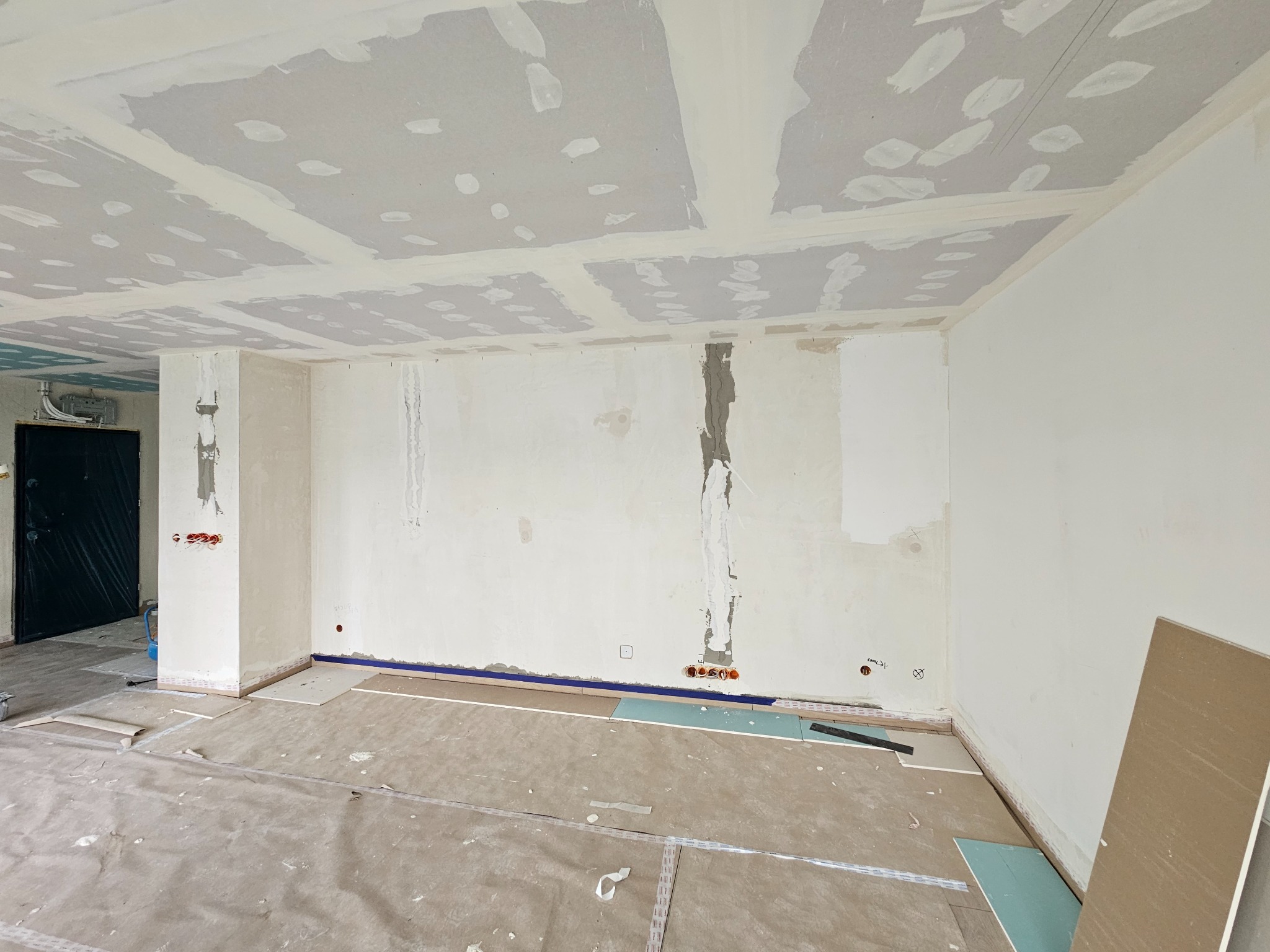 Wnętrze w trakcie remontu: płyty karton-gips na suficie i ścianach, szpachlowanie połączeń, zabezpieczona folią podłoga, widoczne puszki elektryczne.