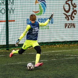 BABCZYŃSKI IT Piotr Babczyński - Młody piłkarz w neonowo-żółtym stroju, kopiący piłkę na boisku w Szczecinie, z siatką bramki i logo PZPN w tle.