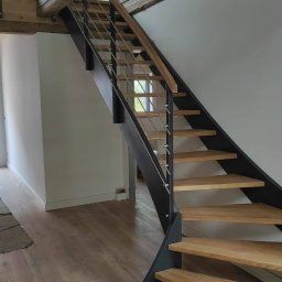 PEKA WOODCRAFT SPÓŁKA Z OGRANICZONĄ ODPOWIEDZIALNOŚCIĄ - Nowoczesne schody z drewnianymi stopniami, metalową konstrukcją i balustradą z cienkich prętów, w jasnym wnętrzu z drewnianymi belkami stropowymi.