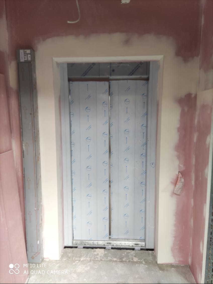 Montaż sufitu napinanego: widoczne profile i folia ochronna na panelach. Ściany w trakcie szpachlowania, widoczne ślady gipsu. Prace w toku.