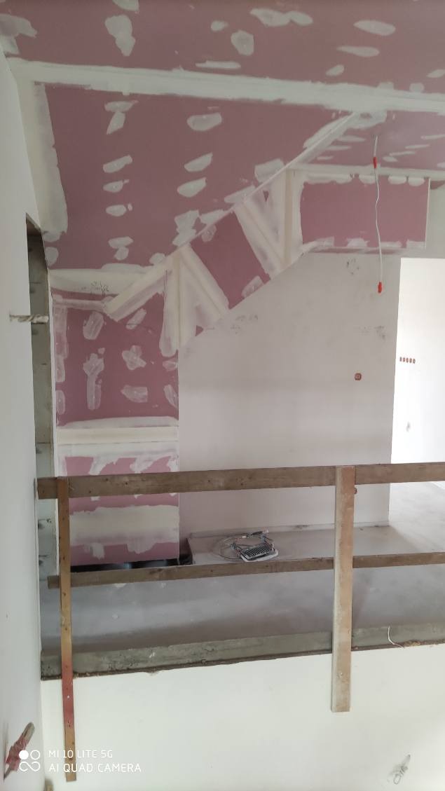 Montaż płyt gipsowo-kartonowych na suficie poddasza z widocznymi elementami konstrukcyjnymi i miejscami łączeń. Widoczne szpachlowanie. Etap prac wykończeniowych.