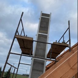 Ihor Kadynskyi - Budowa domu w Świebodzinie: widok na wznoszone ściany z betonu komórkowego, rusztowanie i konstrukcję dachu w trakcie montażu, pochmurne niebo w tle.