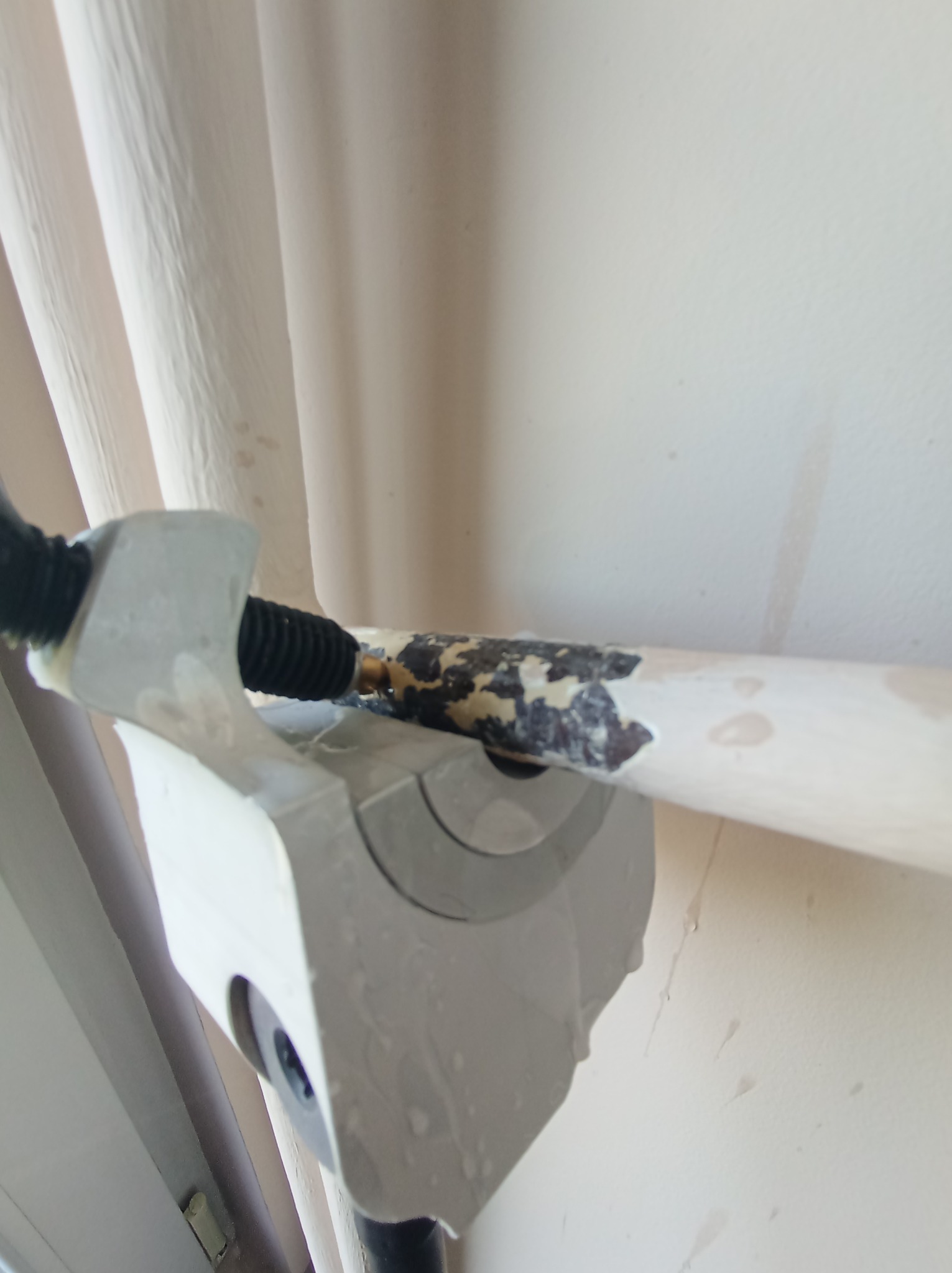 Nisko kątowe ujęcie fragmentu instalacji grzewczej z rurą pokrytą odpryskującą farbą, widoczne ślady po cieknącej wodzie na ścianie.