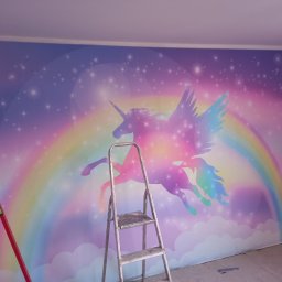 Aa bud - Pokój po remoncie z fototapetą przedstawiającą tęczowego jednorożca ze skrzydłami na tle gwiazd, widoczna drabina malarska i poziomica.