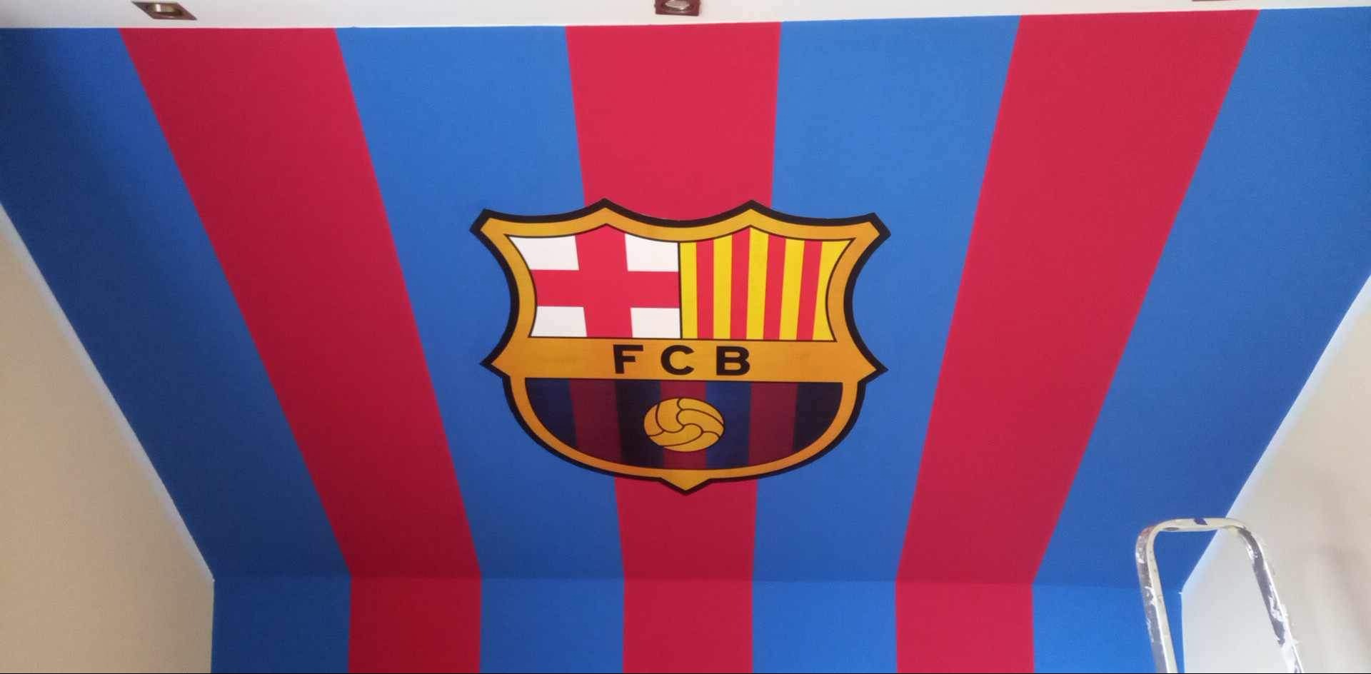 Pomieszczenie z pomalowanym sufitem w niebiesko-czerwone pasy z herbem FC Barcelony, widoczny fragment drabiny.