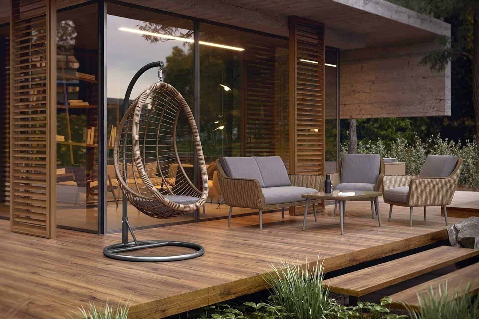 Zadaszony taras z drewnianą podłogą w Mierzynie, wyposażony w wiklinowy fotel wiszący, sofę i dwa fotele z szarymi poduszkami oraz stolik kawowy, widok na ogród przez duże okno.